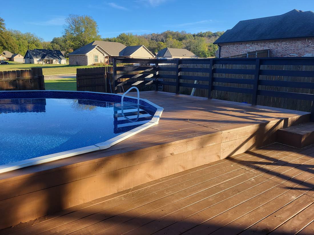 Second finished pool deck project with black slat railing wrapping the corner