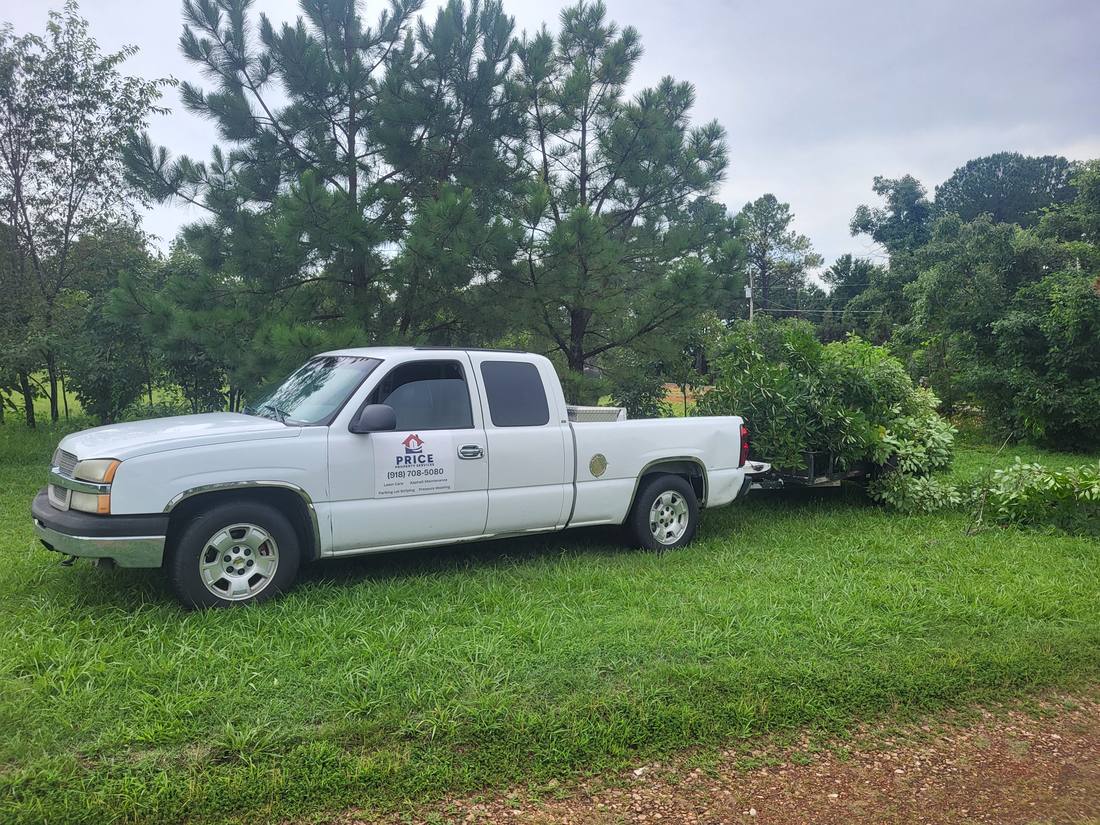 Price Property Services branded truck hauling a trailer of cleared brush and debris