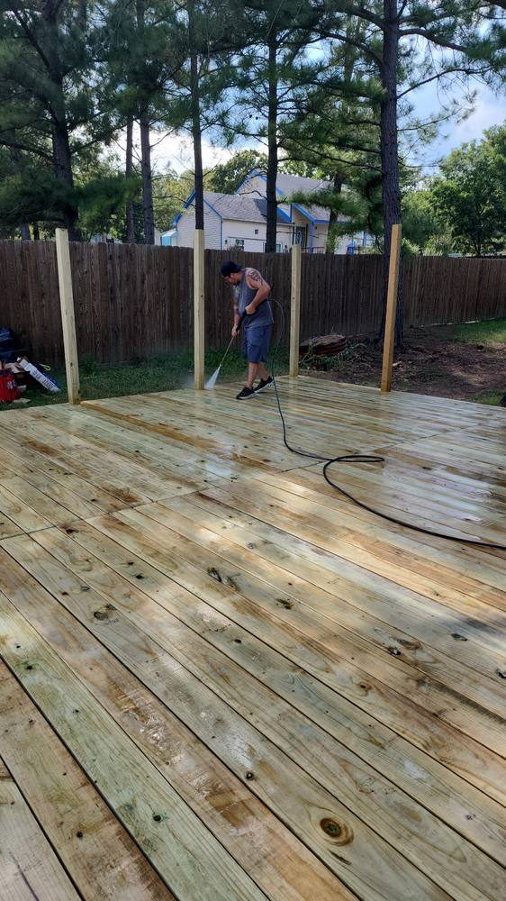 Crew member pressure washing a newly built wood deck